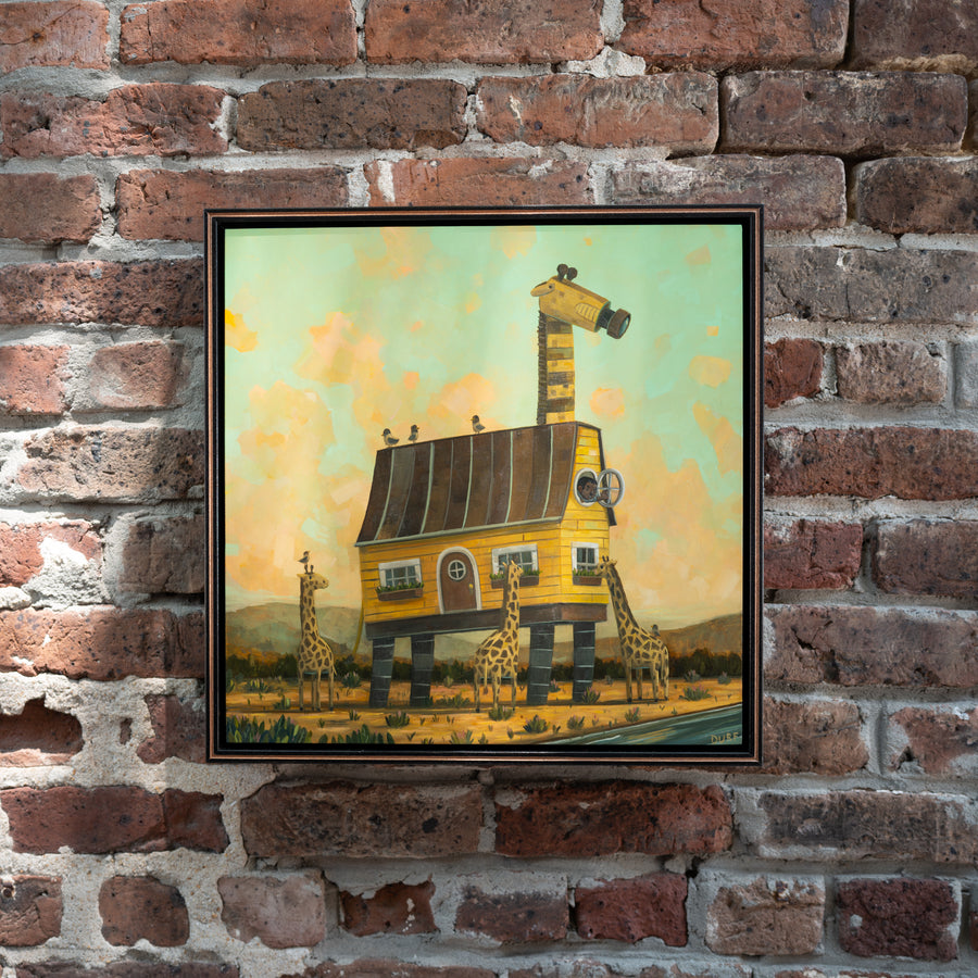 Joining the Journey by Nathan Durfee, painting with giraffes and a yellow house, framed on wall